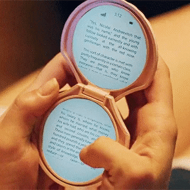 A gif of some fantasy-tech AKA an e-reader that is shaped like a circular flip-open old beauty mirror
