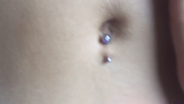 Gif of a shiny belly button piercing and a hand rubbing it slightly.