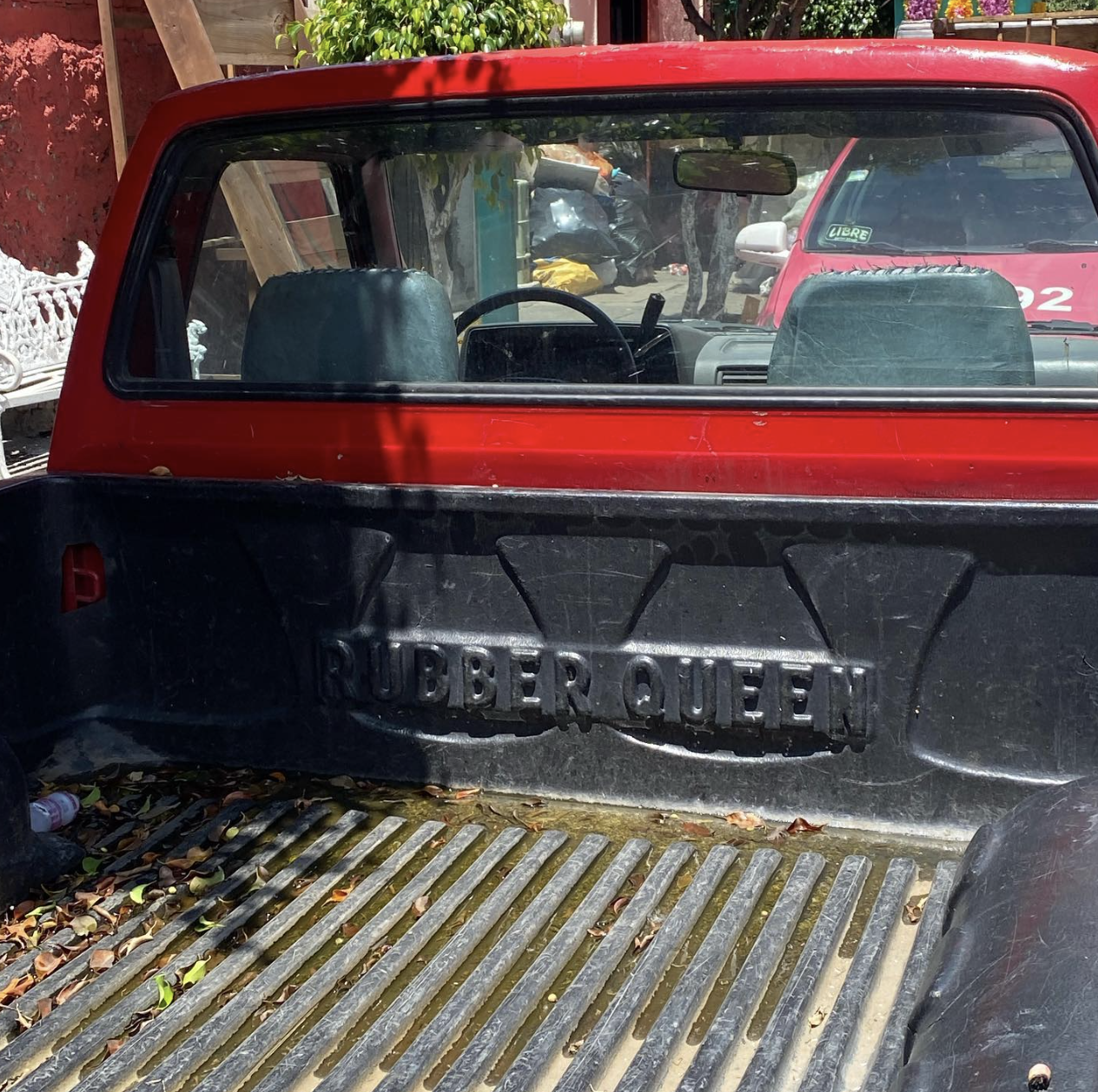 Back of a red ute in mexico reading 'RUBBER QUEEN'. Innuendo for being a queen in the rubber fetish community.